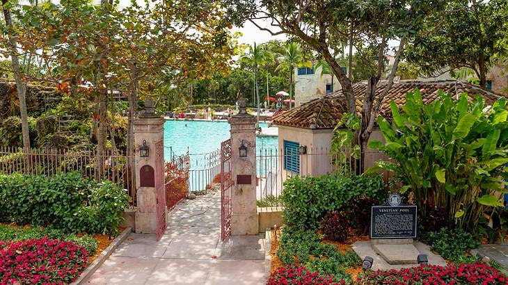 A garden with a stone gate leading to a swimming pool