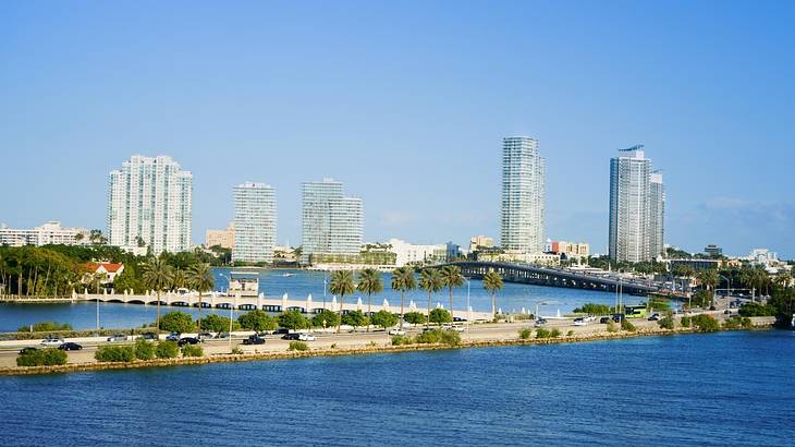 A causeway over water with cars on it and buildings in the background