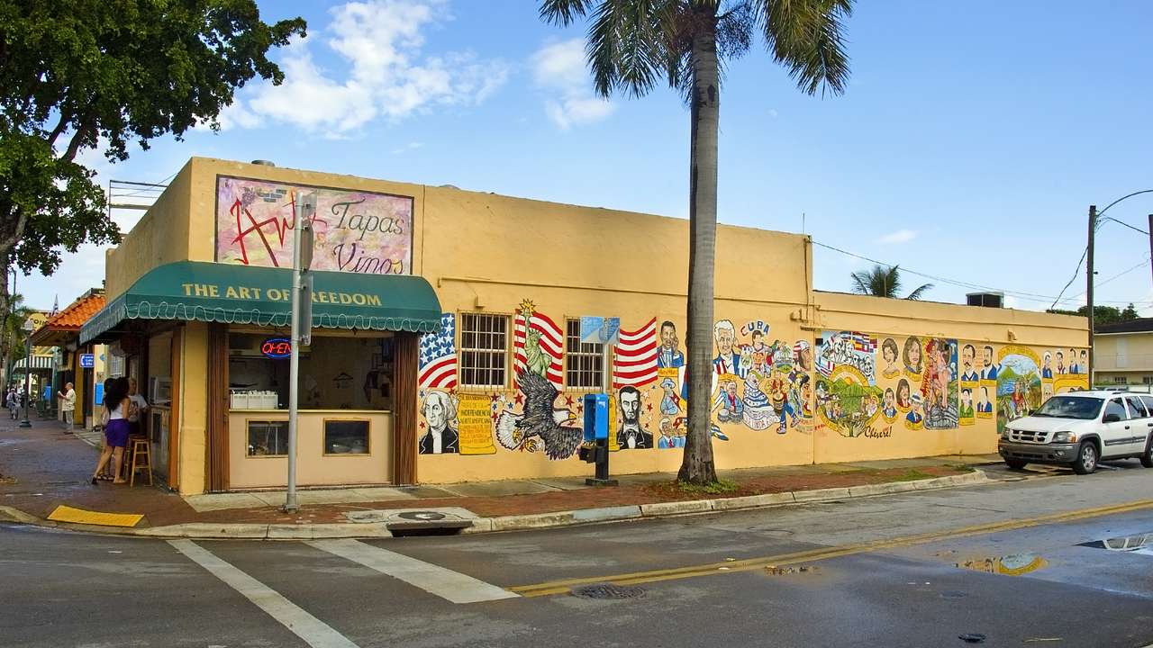 A yellow building with green awning and murals on the side with a road in front