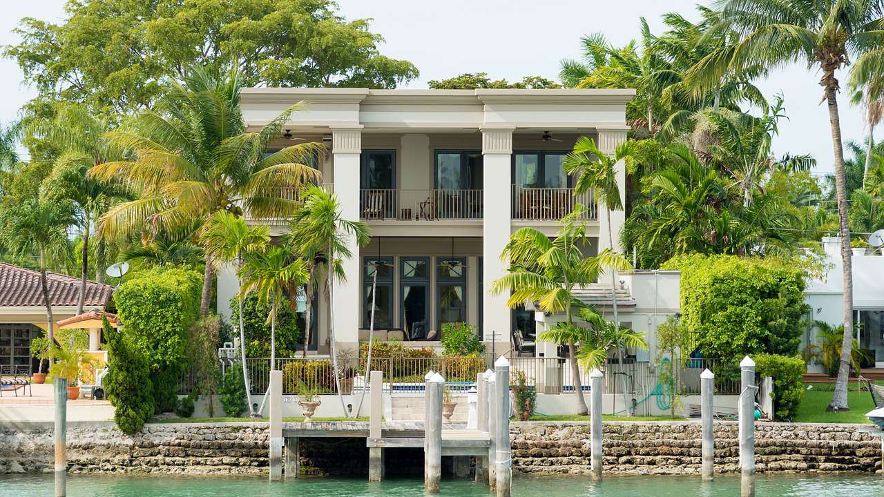 A luxury waterfront home with palm trees surrounding it