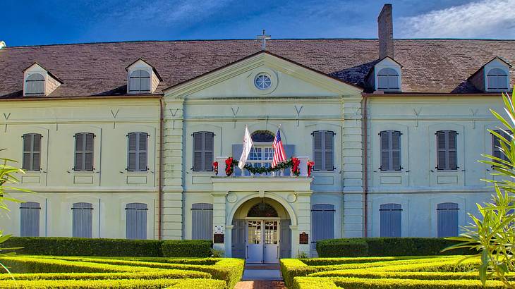 A structure with many windows and flags on top of its door near a landscaped garden