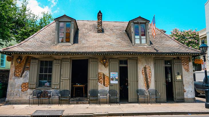 An old bricked house with chairs in front under a blue sky