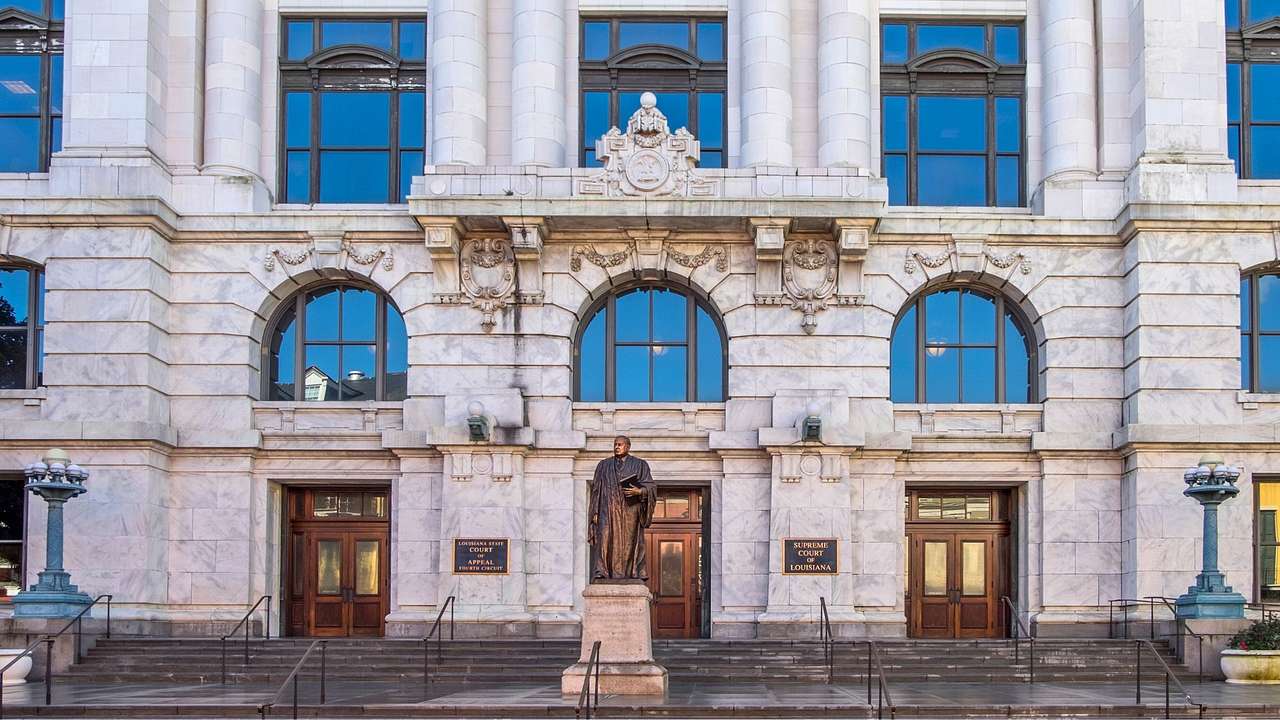 A Beaux-Arts-style building with stone columns and a bronze statue in front