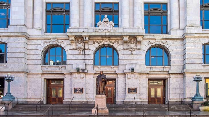 A Beaux-Arts-style building with stone columns and a bronze statue in front