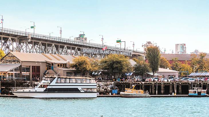 A boat docked by a harbor near structures and trees