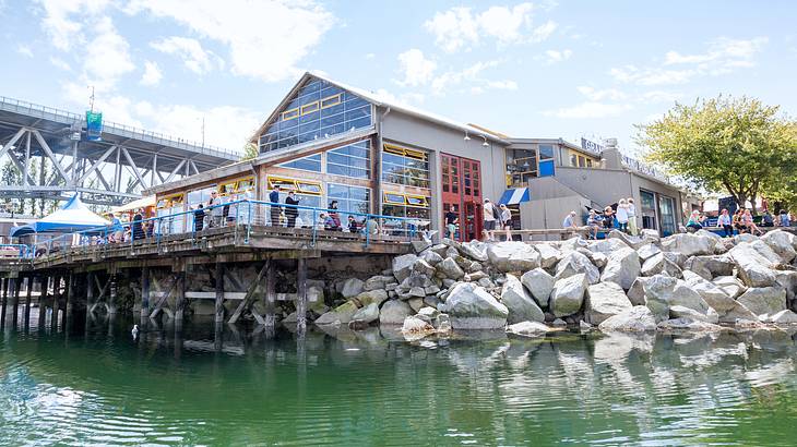 A building with a glass facade facing a body of water against a bridge