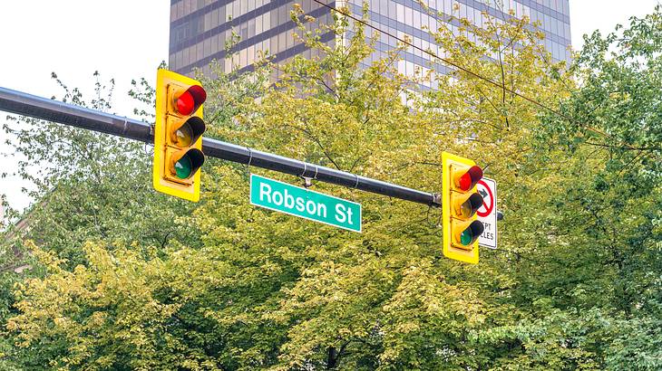 A photo of the Robson Street sign with traffic lights against green trees