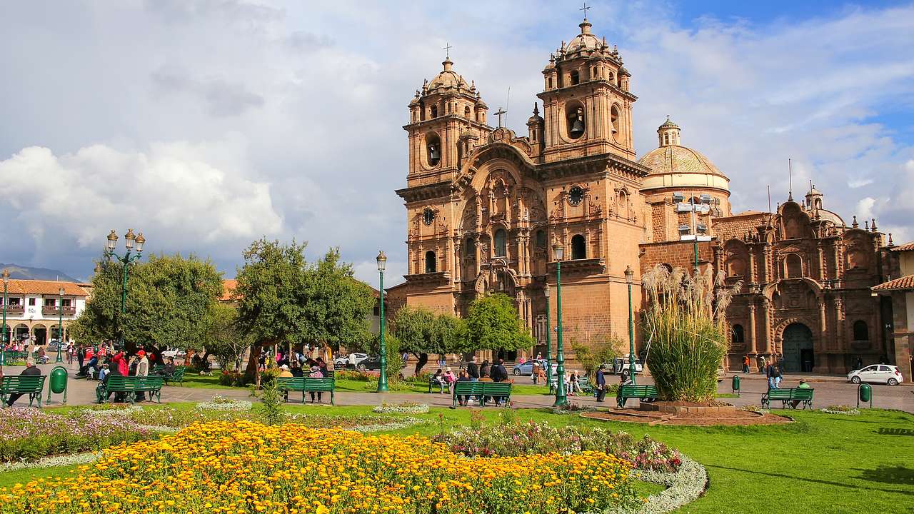 A large building with two towers and a dome facing a garden with yellow flowers