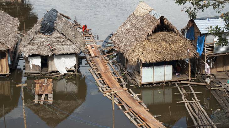 Aerial view of wooden homes along a river in a village with a floating wooden pathway