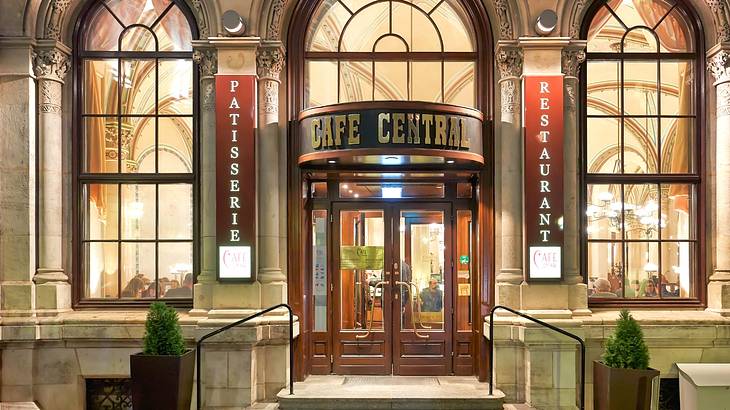 The entry of a luxury cafe with arched windows and a sign that says "Cafe Central"