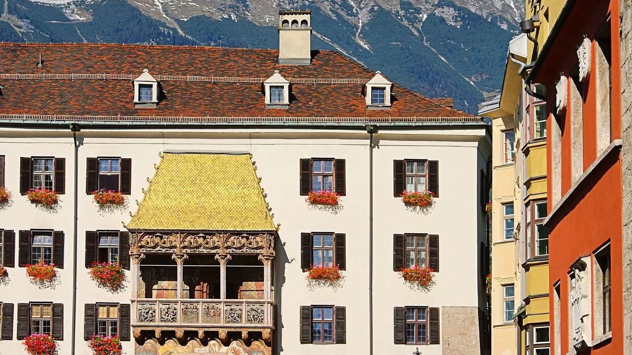 A European Alpine-style building with a balcony with a golden roof attached