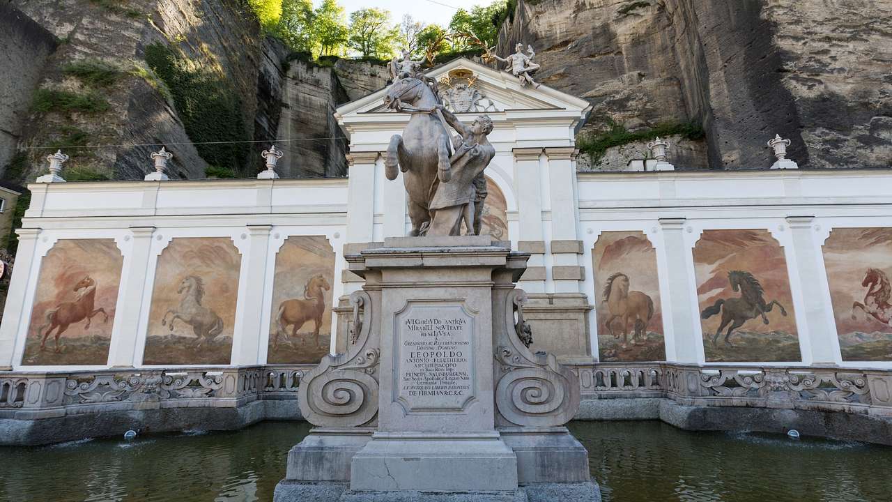 A statue of a horse and a horse tamer on a pedestal in a pond