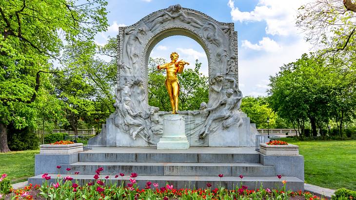 An arch-shaped monument with a gold statue of a man playing the violin in the centre