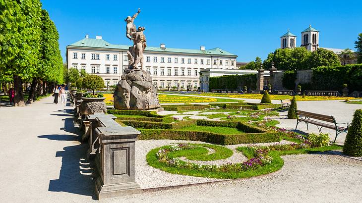 Gardens with a statue and paths around it next to a grand palace