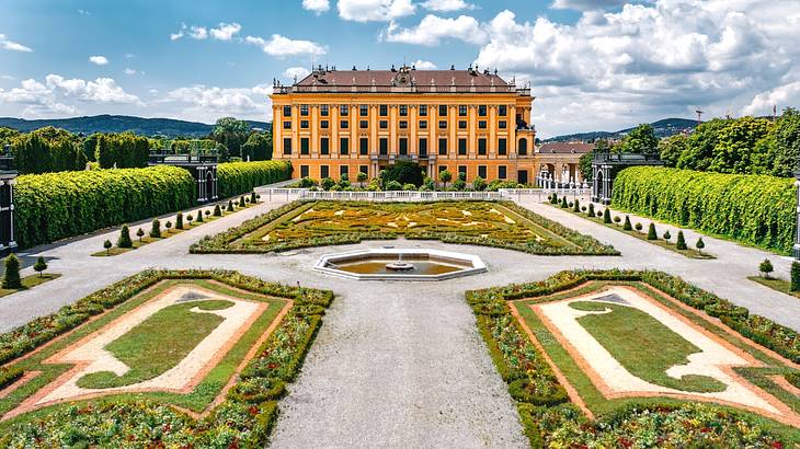 A palace next to a manicured garden with a path and greenery