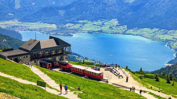 A view of a lake and a small train station from the top of a mountain
