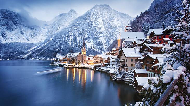 A ski village next to a lake and snow-covered mountains under a grey sky