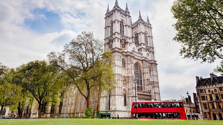 A bottom up view of a beautiful cathedral with trees and a red bus in front