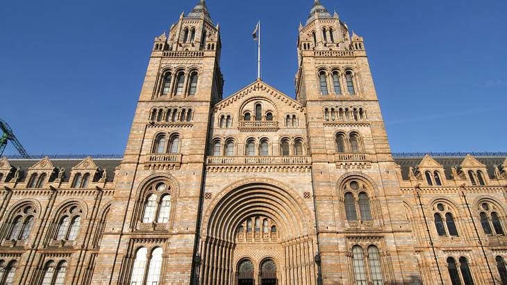 A large stone building with two spires and arched windows under blue cloudless skies