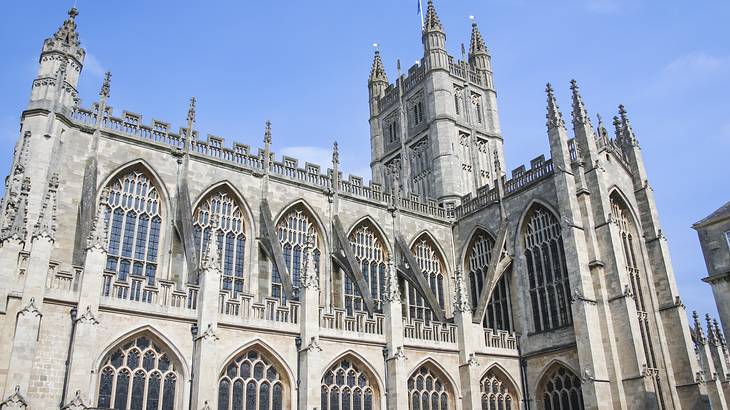 A bottom-up view of a sandstone cathedral with a tower under a blue sky