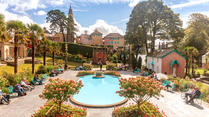 A panoramic view of gardens, a small fountain, blue benches and colourful houses