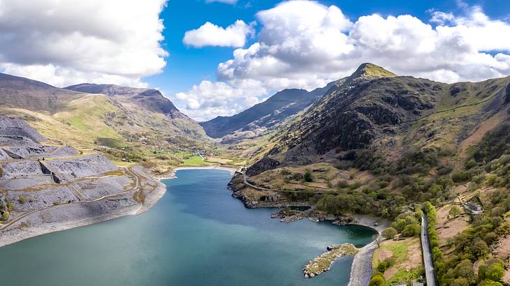 A wide-angle view of a lush green mountainous landscape with a green body of water