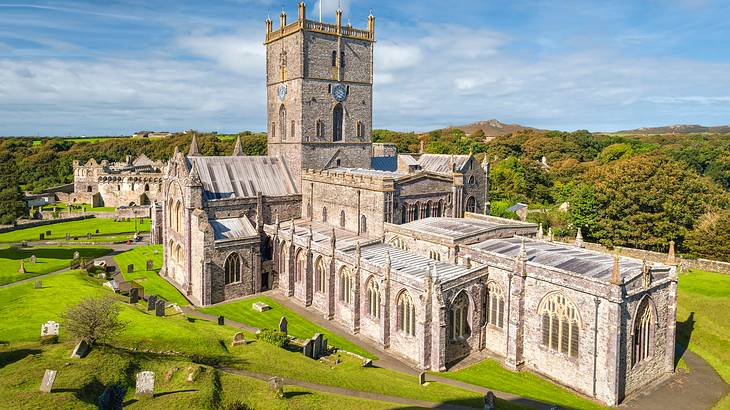 A panoramic view of a Romanesque-style cathedral surrounded by grass and trees