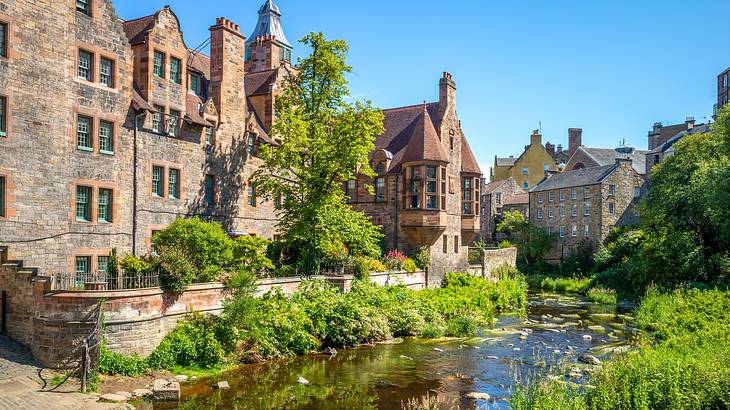 A river flowing through a medieval village surrounded by trees and buildings