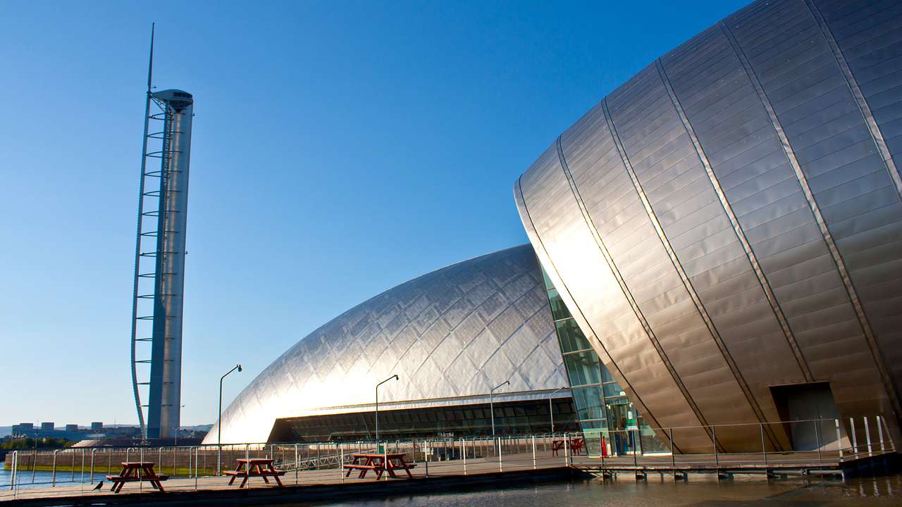 A large building with a domed, metallic silver surface against clear blue skies