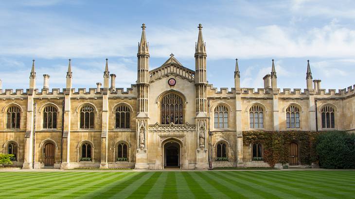 A perfect green lawn in front of a grand college building with spiral tops behind