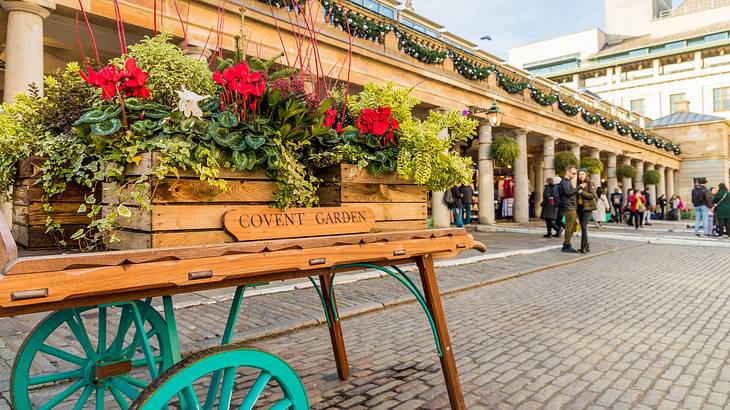 A wooden cart with flowers in front of a building with columns and wreaths on top