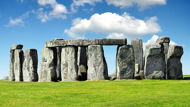 A bunch of large rocks in a circle surrounded by grass under a cloudy sky