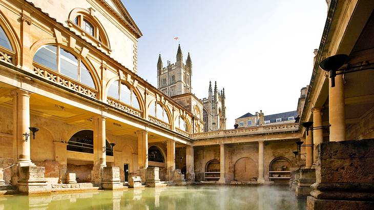 An open-air pool enclosed in a building with columns and stone monuments at the top