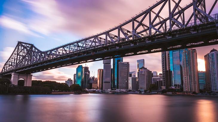 A city skyline full of tall buildings and a bridge in the shadow of a sunset A city skyline full of tall buildings and a bridge in the shadow of a sunset
