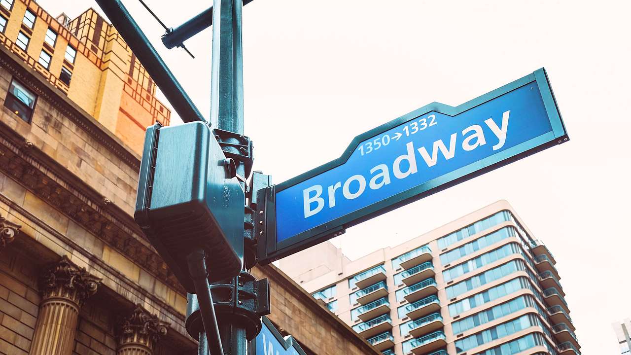 A low-angle close-up shot of a street sign saying "Broadway"