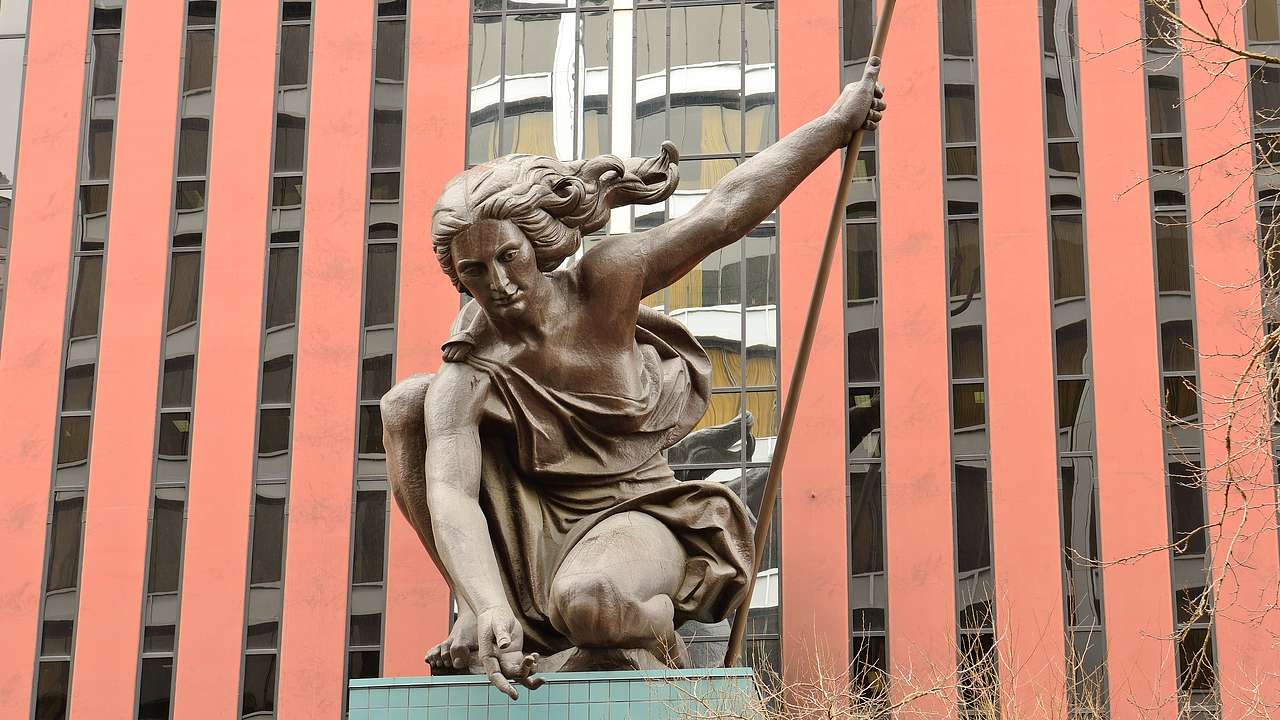 A copper statue of a woman carrying a trident