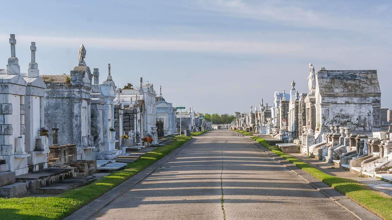 A path in a cemetery with tombs and grass on either side