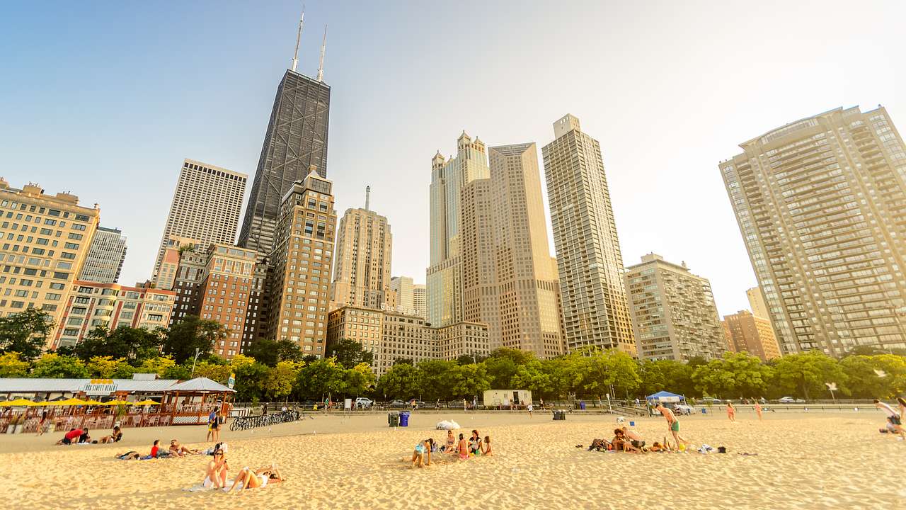People on a white sand beach with trees and buildings in the background