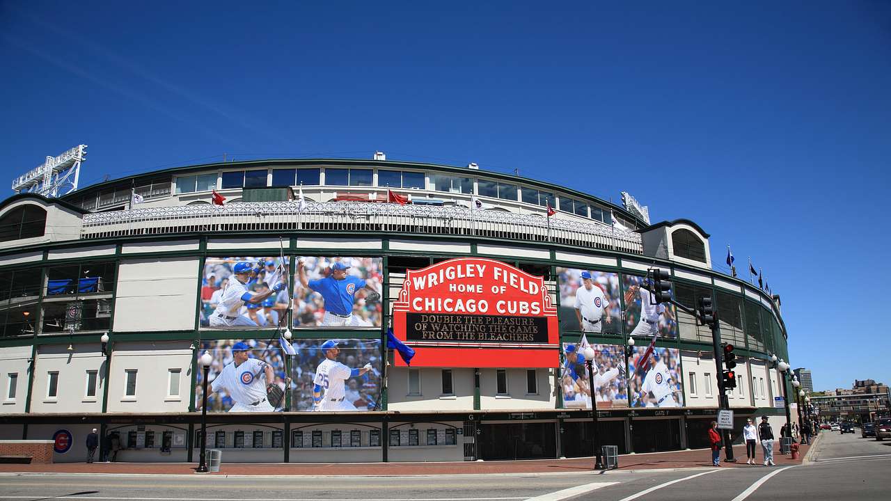 The exterior of a baseball stadium displaying a red sign and photos of players