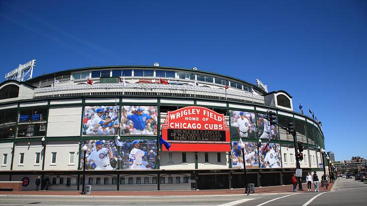 The exterior of a baseball stadium displaying a red sign and photos of players