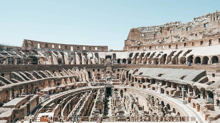 The ancient Roman Colosseum from above with people below on a beautiful blue day
