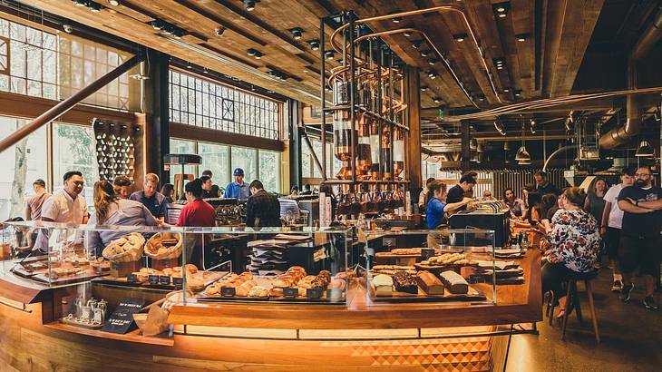 A luxury coffee shop with baked goods on display and people ordering