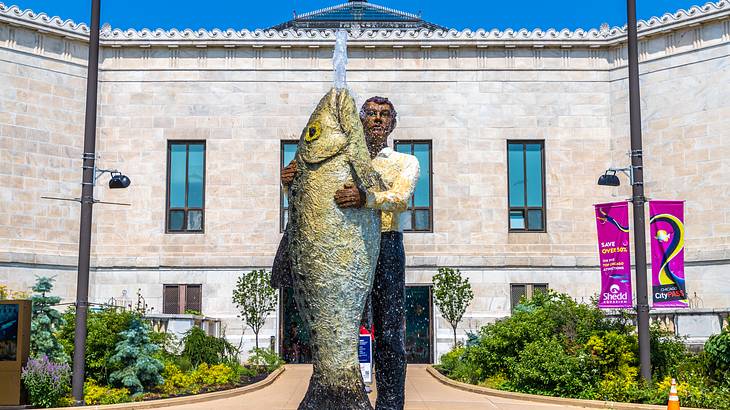 A fountain with a statue of a man holding a large fish spouting water