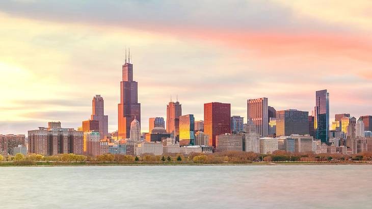 A skyline with water in front of it at sunset