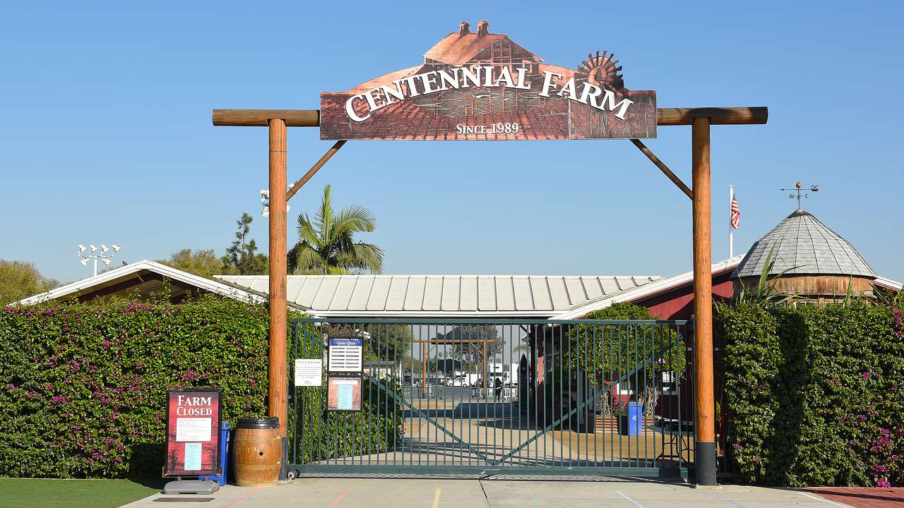 A gate entrance with signage saying "Centennial Farm" near a silo