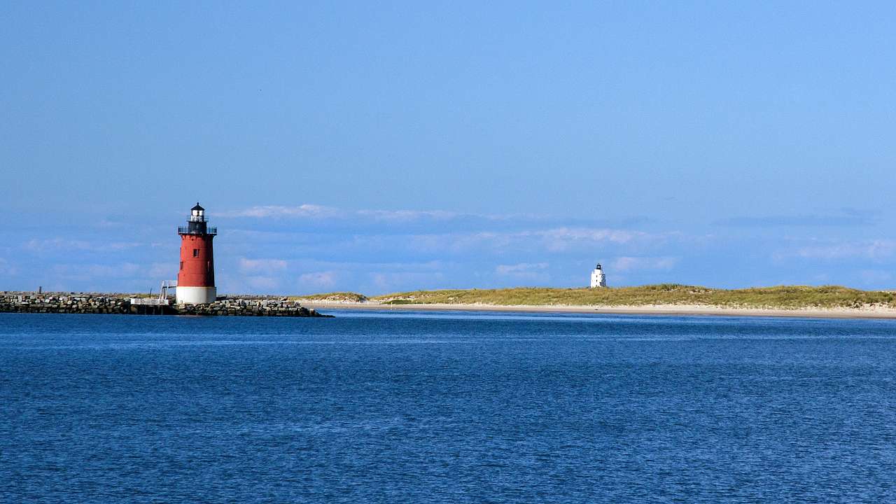 A red and white lighthouse near the sea under a blue sky