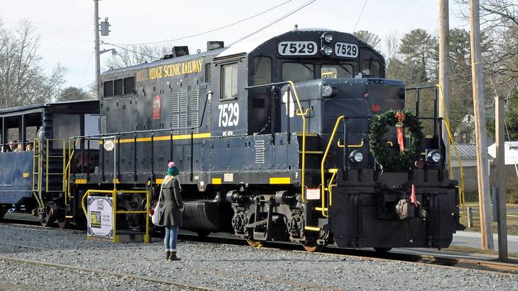 A woman standing near a black railroad train
