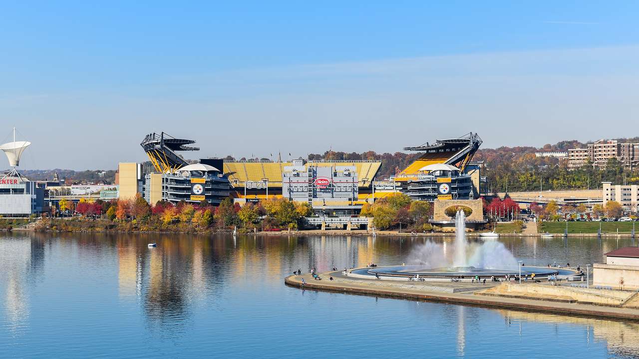 A yellow stadium next to a body of water under a blue sky