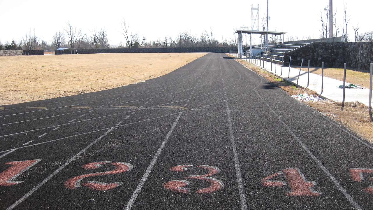 A numbered starting line of a track field with bleachers on its right side
