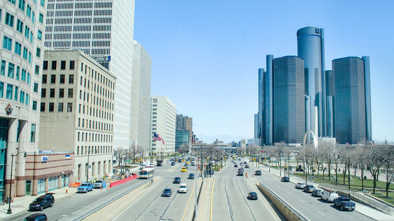 A highway with cars bordered by tall skyscrapers on a sunny day